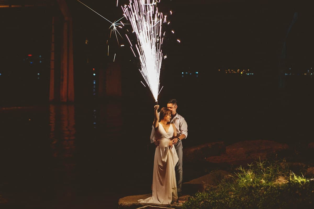 A couple beneath a spark fountain at night